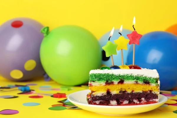 Piece of birthday cake with candles on yellow background, space for text