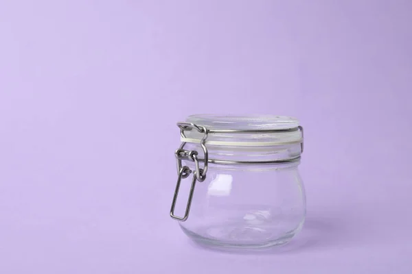 Closed empty glass jar on lilac background