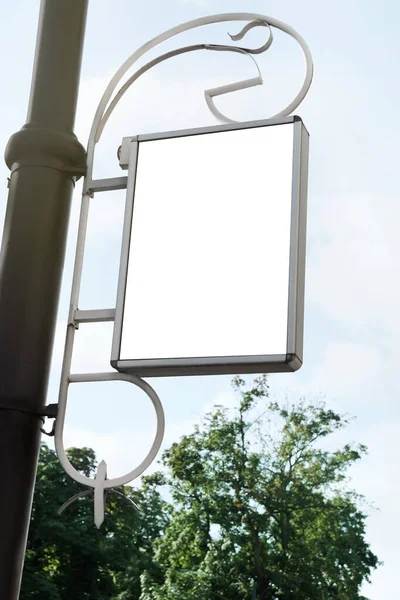 Blank poster on city street, low angle view. Space for design