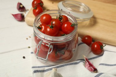 Pickling jar with fresh ripe cherry tomatoes and spices on white wooden table