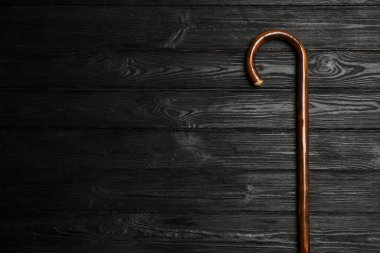 Elegant walking cane on black wooden table, top view. Space for text