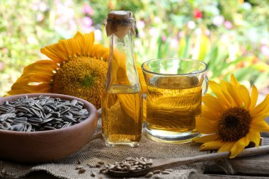 Sunflower oil and seeds on wooden table outdoors