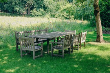 Empty wooden table with bench and chairs on sunny day outdoors