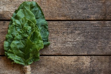 Bunch of beetroot leaves on wooden table, top view. Space for text