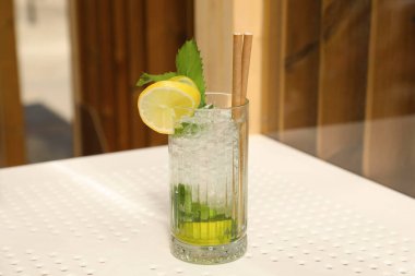 Glass of refreshing citrus drink on white table indoors