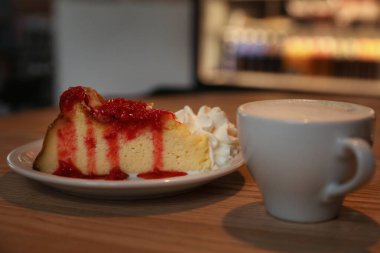 Cup of aromatic coffee and delicious dessert on wooden table in cafe, closeup