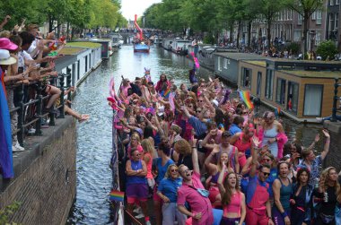 AMSTERDAM, NETHERLANDS - AUGUST 06, 2022: Many people in boats at LGBT pride parade on river