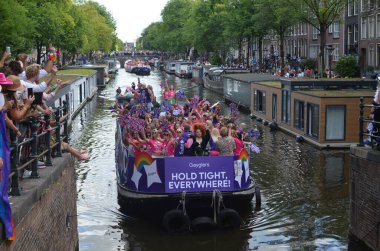 AMSTERDAM, NETHERLANDS - AUGUST 06, 2022: Many people in boats at LGBT pride parade on river