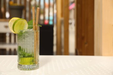 Bir bardak ferahlatıcı narenciye içeceği beyaz masa içinde, mesaj için yer var.