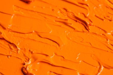 Beautiful strokes of orange oil paint as background, closeup