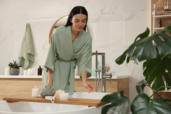 Beautiful young woman near tub in bathroom