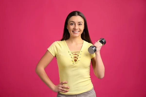 Woman with dumbbell as symbol of girl power on pink background. 8 March concept