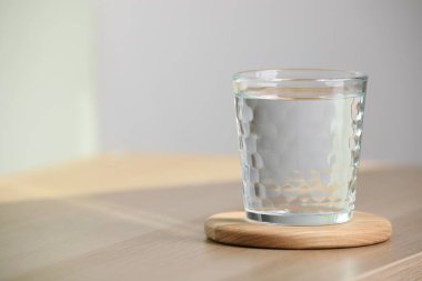 Glass of pure water on wooden table indoors, space for text