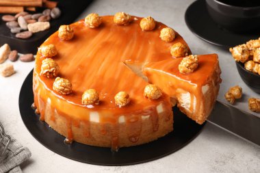 Delicious caramel cheesecake with popcorn on light grey table, closeup