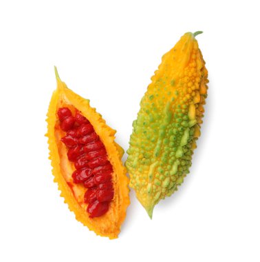 Whole and cut ripe bitter melons on white background, top view