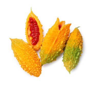 Whole and cut ripe bitter melons on white background, top view