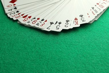 Fan of playing cards on green table. Space for text