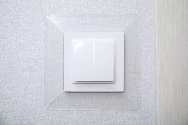 Modern plastic light switch on white wall, closeup