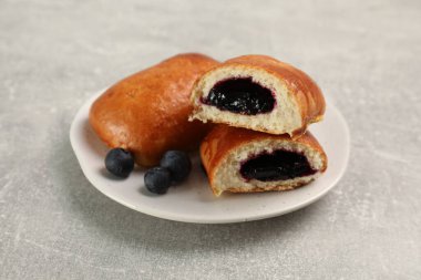 Delicious baked patties with blueberries on light grey table