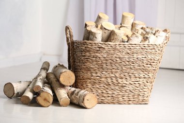 Beyaz zeminde kesilen odunlarla dolu bir sepet.
