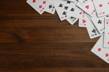 Playing cards on wooden table, flat lay. Space for text