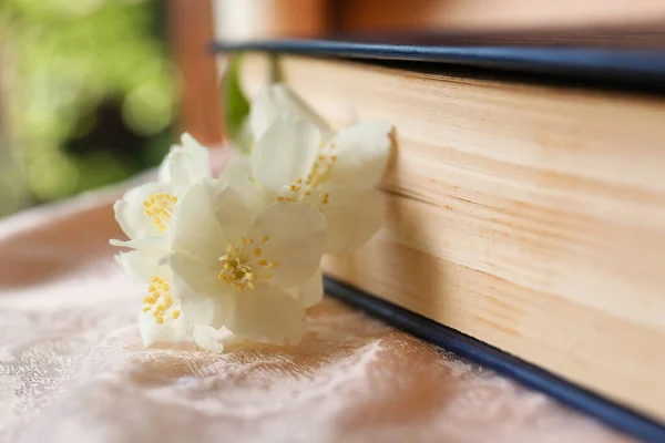 Beautiful jasmine flowers near book on pink fabric, closeup