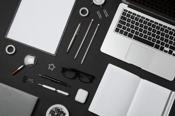 Flat lay composition with laptop and stationery on black background. Designer\'s workplace