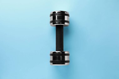 Stylish dumbbell on light blue background, top view