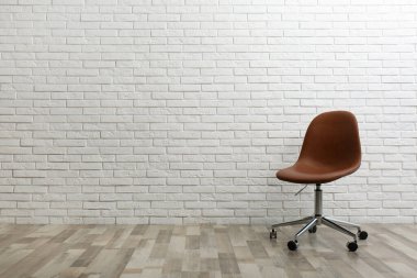 Beyaz tuğlalı duvarın yanında rahat bir ofis sandalyesi. Metin için boşluk