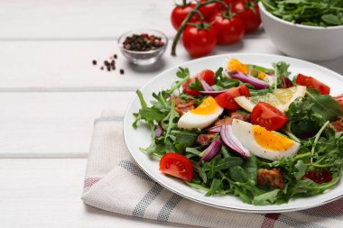 Delicious salad with boiled eggs, vegetables and bacon on white wooden table, closeup. Space for text