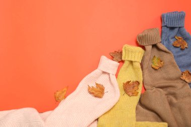 Sıcak süveterler ve turuncu arka planda kuru yapraklar, metin için yeri olan düz bir yer. Sonbahar mevsimi