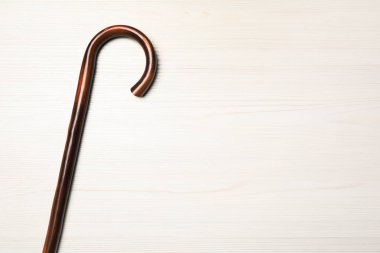 Walking cane on white wooden background, top view. Space for text