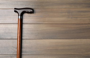 Walking cane on wooden background, top view. Space for text