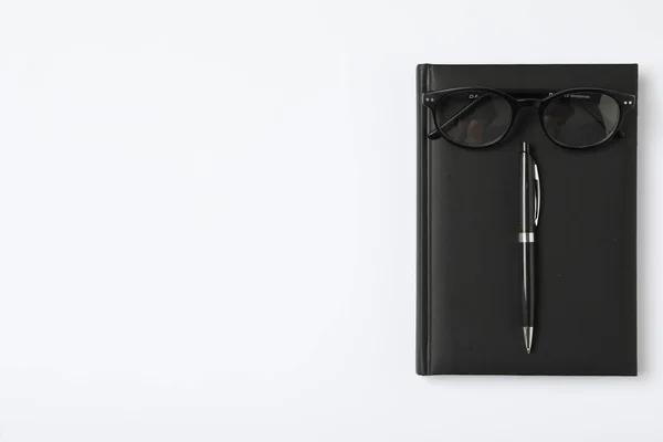 Notebook, pen and eyeglasses on white background, flat lay with space for text. Teacher's Day