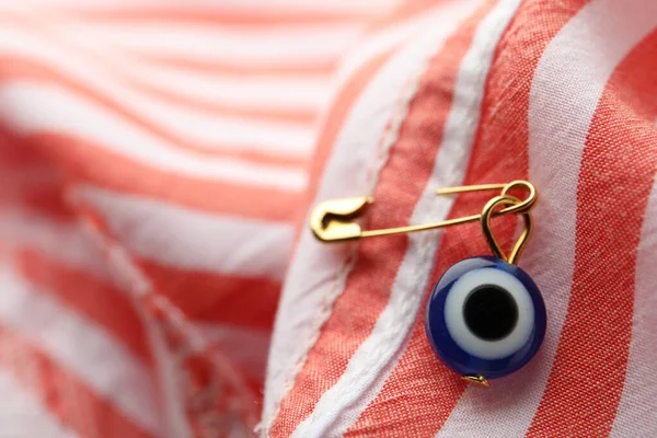 Evil eye safety pin on clothing, closeup