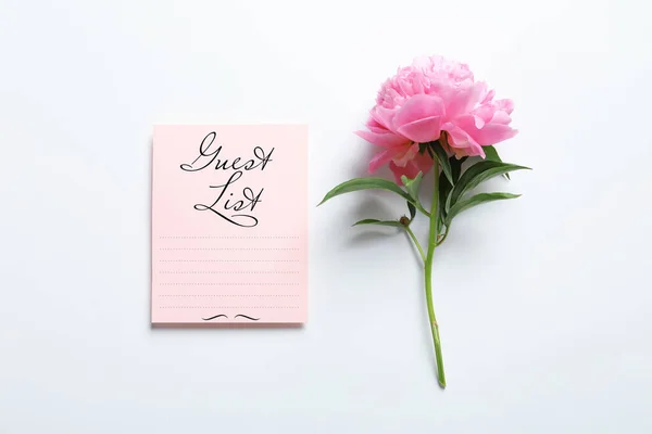 Guest list and beautiful peony on white background, top view