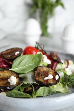 Delicious salad with roasted eggplant, basil and cheese on plate, closeup