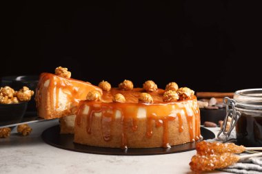 Taking piece of delicious caramel cheesecake with popcorn on light grey table