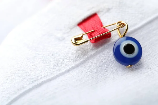 Evil eye safety pin on clothing, closeup