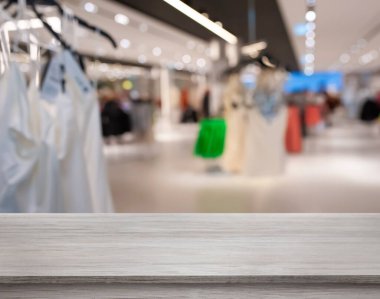 Empty wooden surface and blurred view of clothes store interior. Space for design