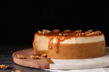 Delicious cheesecake with caramel and walnuts on black marble table