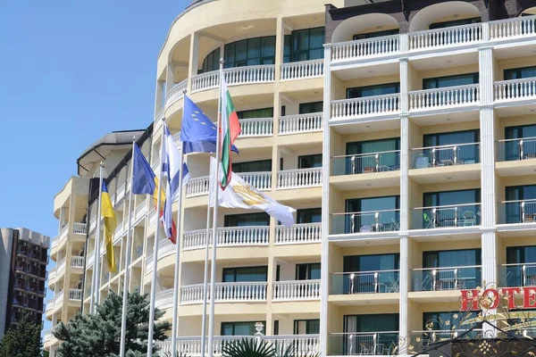 Many different flags near modern hotel on sunny day