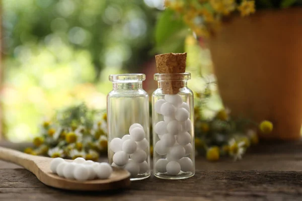 Bottles of homeopathic remedy and flowers on wooden table