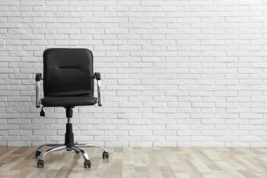 Beyaz tuğlalı duvarın yanında rahat bir ofis sandalyesi. Metin için boşluk