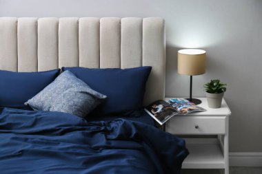 Odasında zarif ipek çarşaflar olan bir yatak.