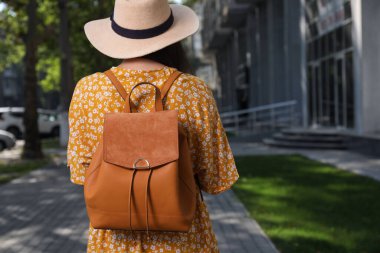 Young woman with stylish backpack on city street, back view