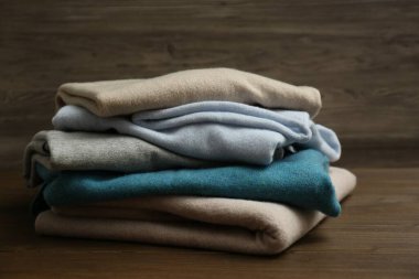 Stack of cashmere clothes on wooden background