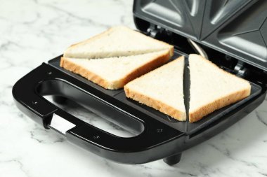 Modern sandwich maker on white marble table, closeup