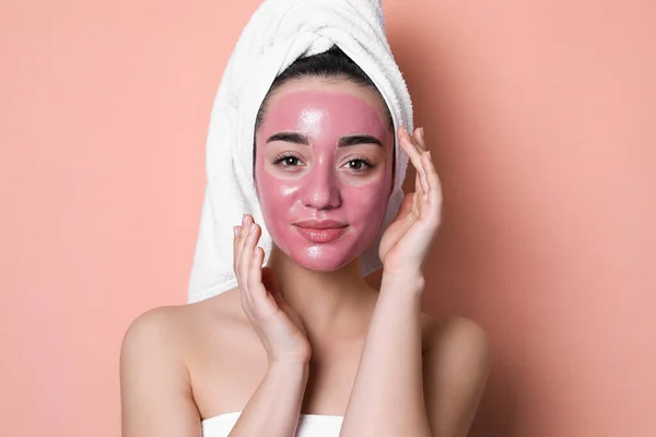 Woman with pomegranate face mask on pale coral background