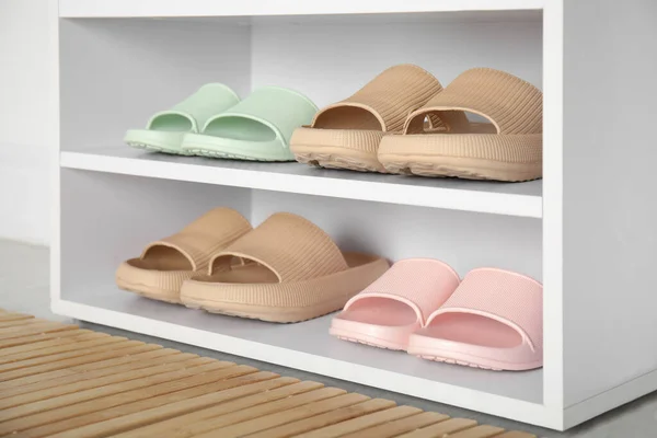 Storage cabinet with different pairs of rubber slippers indoors